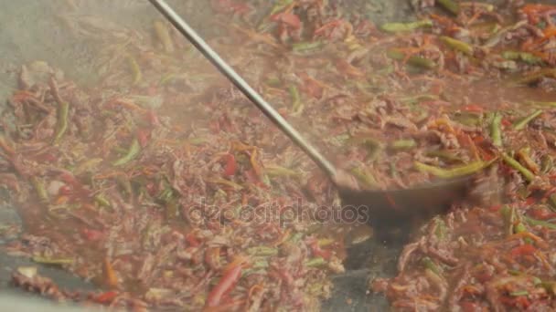 Металева совок змішує азіатську їжу, готуючи на великому горщику — стокове відео