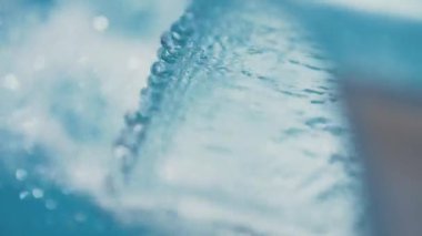 Ağır çekim yay metal şelale mavi yüzme havuzundan içine dökülen su