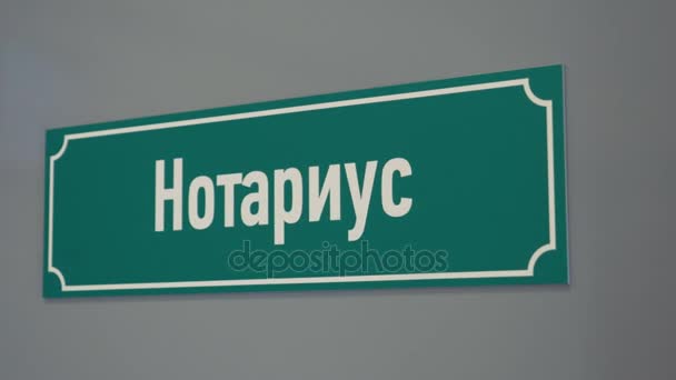 Πράσινη πλαστική πινακίδα στην πόρτα με Κυριλλικό κείμενο ΑΟΕ συμβολαιογράφος — Αρχείο Βίντεο
