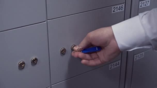 Руки управляющего банком кладут два ключа в сейфовые замочные скважины — стоковое видео