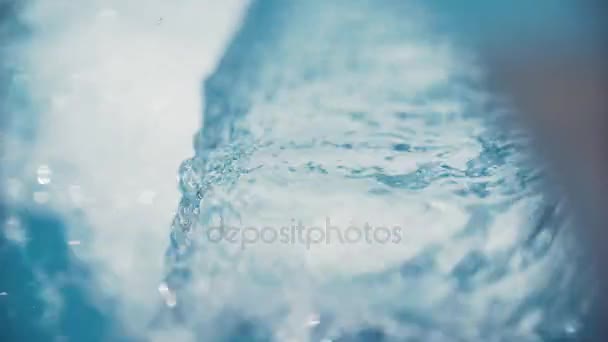 Кривая воды, льющейся в голубой бассейн из металлического водопада — стоковое видео