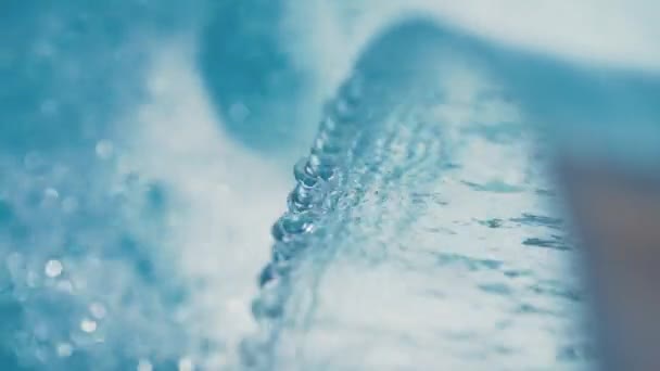 Zeitlupenkurve des Wassers, das von einem metallenen Wasserfall in ein blaues Schwimmbad strömt — Stockvideo