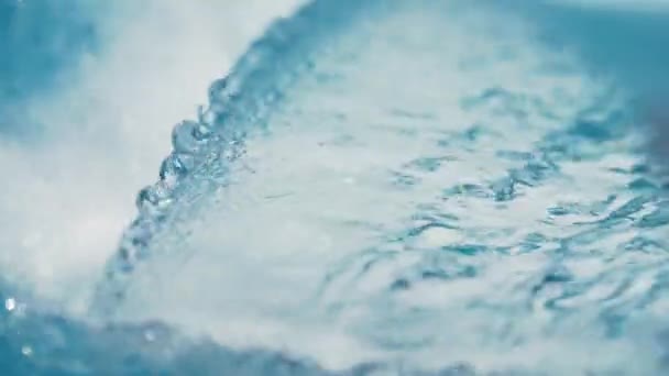 Slow motion arc of water running into blue swimming pool from metal waterfall — Stock Video