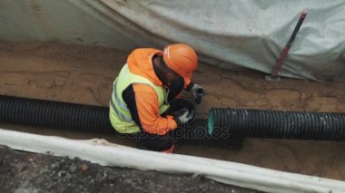Turuncu zor şapka siyah plastik tüp hendek yağ huzur içinde oturan işçi