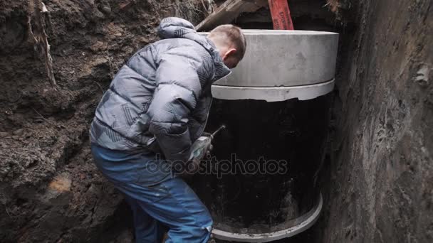 Mann bohrt Loch in Betonkammer-Schachtring im Graben — Stockvideo