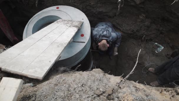 Człowiek, wbijania pin metalu do betonu komory cysterny pierścień w wykopie — Wideo stockowe