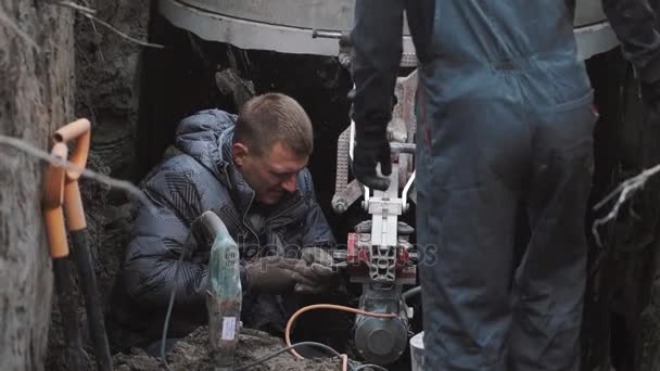 Man gathering big industrial drill in dirty ditch with wrench. Slowmotion — Stock Video