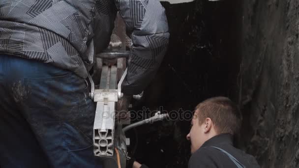 Los trabajadores ponen taladro industrial en la pared del anillo de alcantarilla de hormigón en zanja de alcantarillado — Vídeos de Stock
