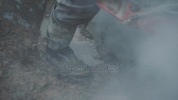 Lots of dust and smoke producing by worker saw concrete in dirt ditch. — Stock Video