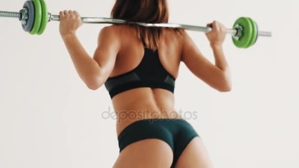 Gran cuerpo deportivo chica haciendo sit ups con barra de pesas en brillante gimnasio blanco — Vídeo de stock