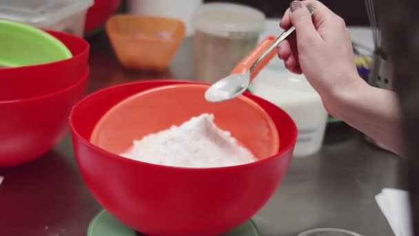 Woman pastry chef hand puts spoon of baking powder into flour in mixing sieve — Stock Video