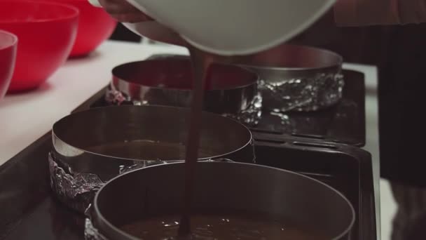 Ženy ruce rozlít čokoládové těsto do pekáčku v kuchyni — Stock video