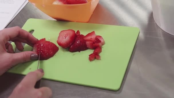 Frauenhände schneiden Erdbeere auf Schneidebrett in Küche auf Metalltisch — Stockvideo