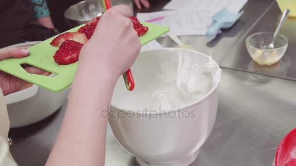女性菓子職人は、ホイップ クリームをボウルに刈り取らイチゴを置く — ストック動画