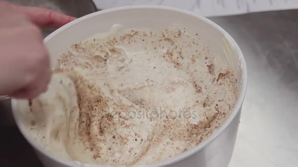 Female confectioner mixing crumbs and whipped cream in mixing bowl using spatula — Stock Video