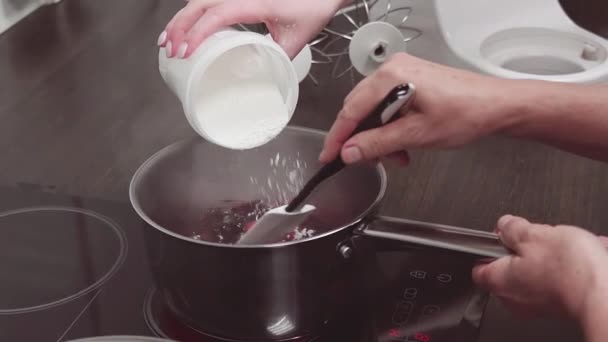 Female hand puts powdered sugar into pan with simmering berries and fruits — Stock Video