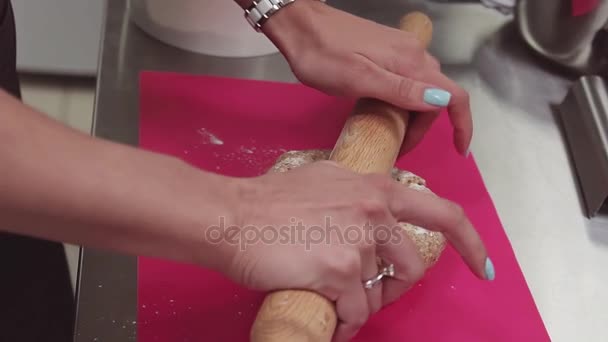在面团上粉红色的切菜板上使用擀面杖的糕点师傅的手 — 图库视频影像