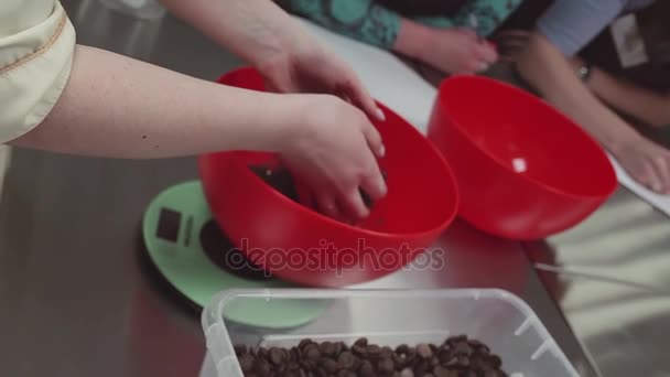 Ženské cukrář klade čokoládové lupínky do mísy na kuchyňské váhy — Stock video