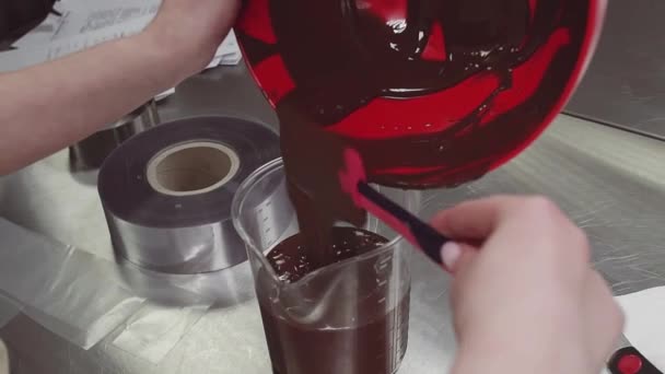 Gebak chef-kok vrouwelijke hand lekkages gesmolten chocolade in het meten van de cup — Stockvideo