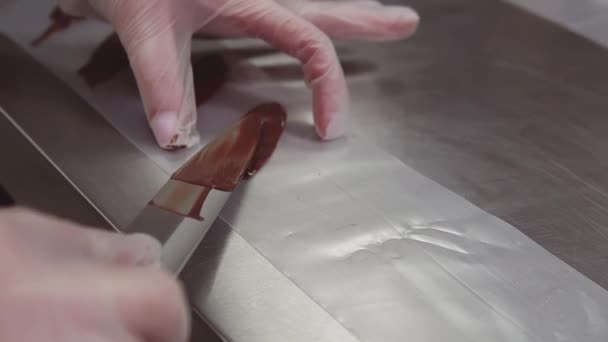 El postre femenino cocinan las manos en guantes de plástico pone chocolate en la tira de cocina — Vídeo de stock