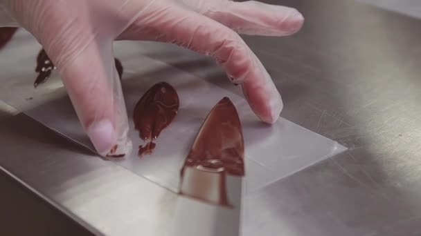 Mujer pastelera manos de chef en guantes de plástico pone chocolate en la tira de cocina — Vídeos de Stock