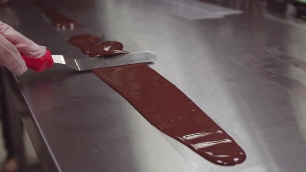 Mulher chef de pastelaria mãos em luvas esfregaços de chocolate derretido usando espátula de gelo — Vídeo de Stock