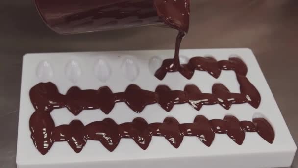 菓子職人が白いプラスチック金型に溶かしたチョコレートを注ぐ — ストック動画