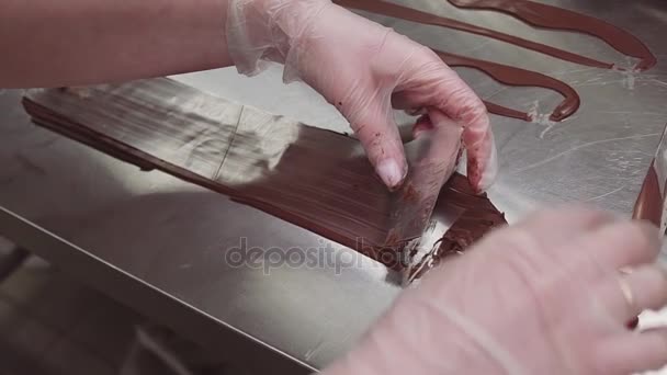 Las manos del chef pastelero tuercen tira de plástico con chocolate en forma de remolino — Vídeos de Stock