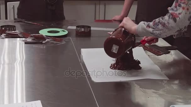 Aprendiz de confeiteiro cai pedaço de chocolate derretido no papel de cozinha — Vídeo de Stock