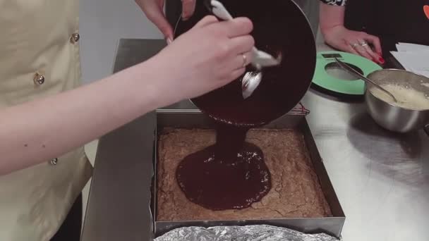 Chef pâtissier verse du chocolat fondu sur bisquit dans une plaque de cuisson — Video