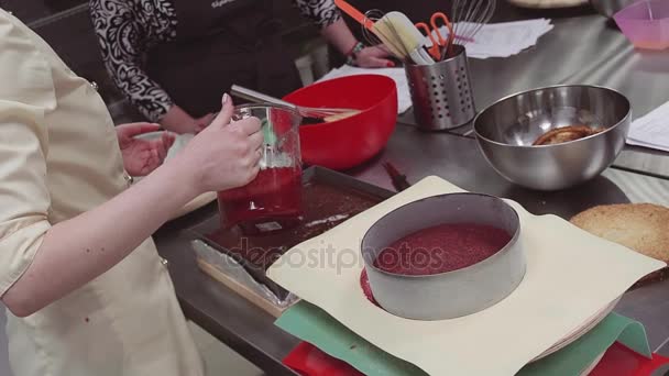 Female confectioner hands pours red sauce into baking tray making cake — Stock Video