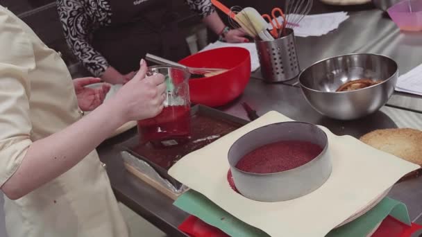 Női cukrászda kezek önti a sütés tálca, így a torta piros mártással