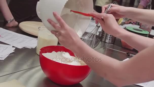 Las manos de chef de pastelería femenina ponen crema batida en un tazón de mezcla usando espátula — Vídeo de stock