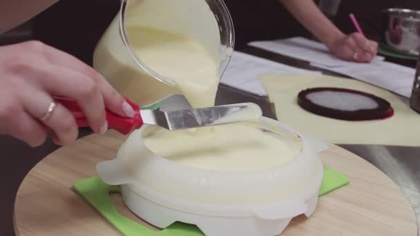 Kvinna konditor häller vaniljsås creme i skålen form på konditori kök — Stockvideo