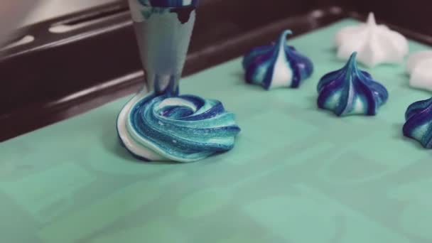 Πολύχρωμο κρέμα squized στροβιλισμού από σακούλα ζαχαροπλαστικής σε ταψί με merengues — Αρχείο Βίντεο