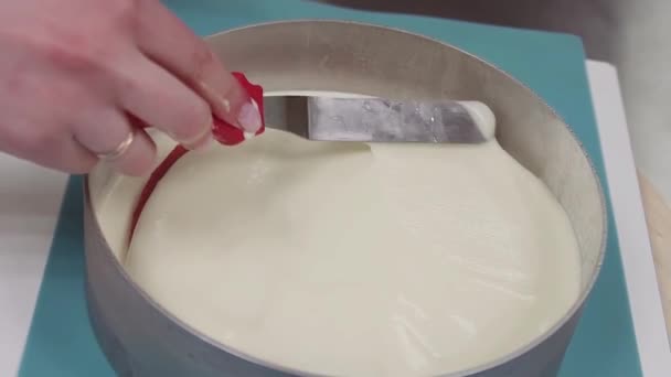 Pastelera femenina con espátula de hielo sobre crema en forma de hornear en el plato giratorio — Vídeos de Stock