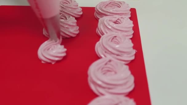 Making merengues spirals squeezing pastry bag on red baking surface — Stock Video