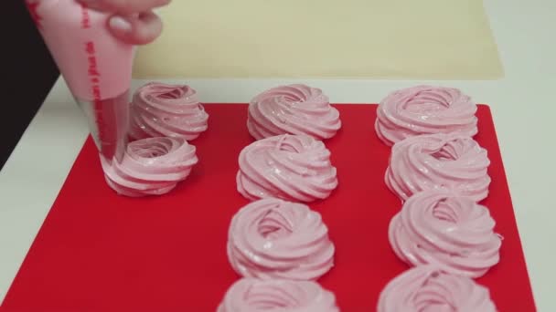 Mujer pastelera chef aprieta bolsa de pastelería haciendo merengues en la tabla de cortar rojo — Vídeos de Stock