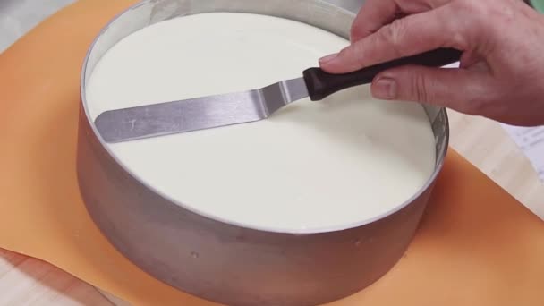 Female pastry cook using icing spatula on creme in baking form on turntable — Stock Video