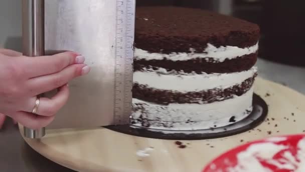 Female confectioner using pastry scraper to take excessive cream of cake — Stock Video