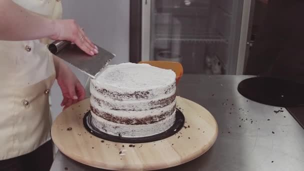 Pâtisserie cuisinière utilisant grattoir à pâtisserie pour prendre la crème excessive de gâteau — Video