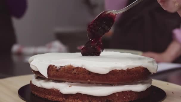 Spoon of berry jam puts on whipped creme on short fruit cake bisquit — Stock Video