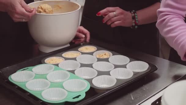 Sobremesa padeiro mão coloca massa em muffins copos de papel de pergaminho na bandeja de cozimento — Vídeo de Stock