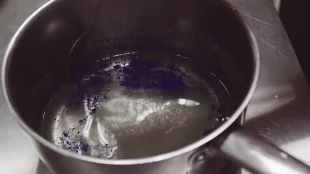 Cocinero revolviendo colorante de comida azul en maceta de metal con agua azucarada — Vídeo de stock