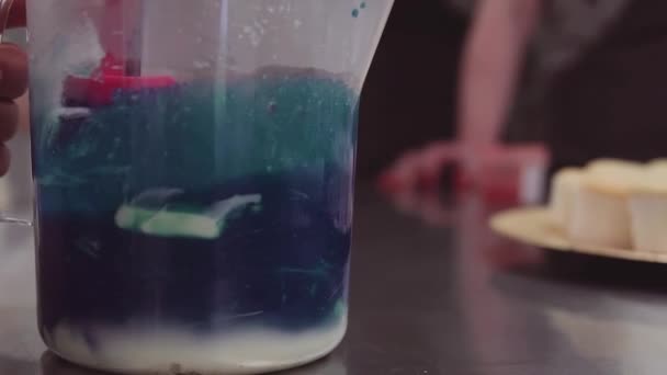 Kék ételfesték keverés tejszínhabbal, mérőpohár — Stock videók