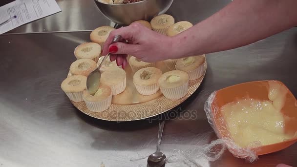 Mão de confeiteiro fêmea coloca creme dentro de muffins cortados câmaras — Vídeo de Stock