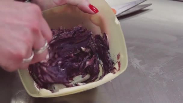 Mains féminines mélangeant crème pâtissière violette colorée dans un bol carré — Video