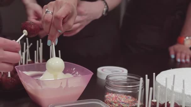 Кондитер готовит групповые руки накрывает десертный шар на палочке в расплавленном шоколаде — стоковое видео
