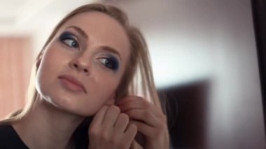 Küpe ayna önünde genç çekici sarışın kız koyar