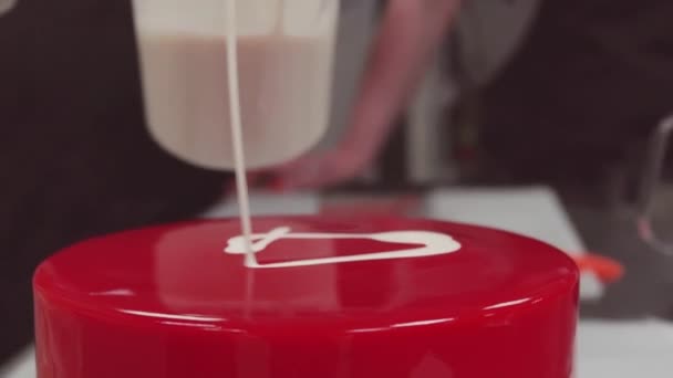Konditor gießt Sahne auf Kuchen rote Spiegelglasur Zuckerguss aus Messbecher — Stockvideo